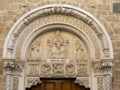 Due grifoni alati sorreggono da entrambi i lati l'arco superiore, a sua volta decorato con bassorilievi di angeli e uomini nell'atto di preghiera. Infine nel lunettone sopra la porta si trova la Vergine seduta in trono col bambino attorniata anch'ella da angeli